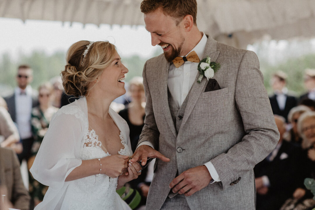 Braut und Braeutigam laecheln sich nach dem Ringtausch an