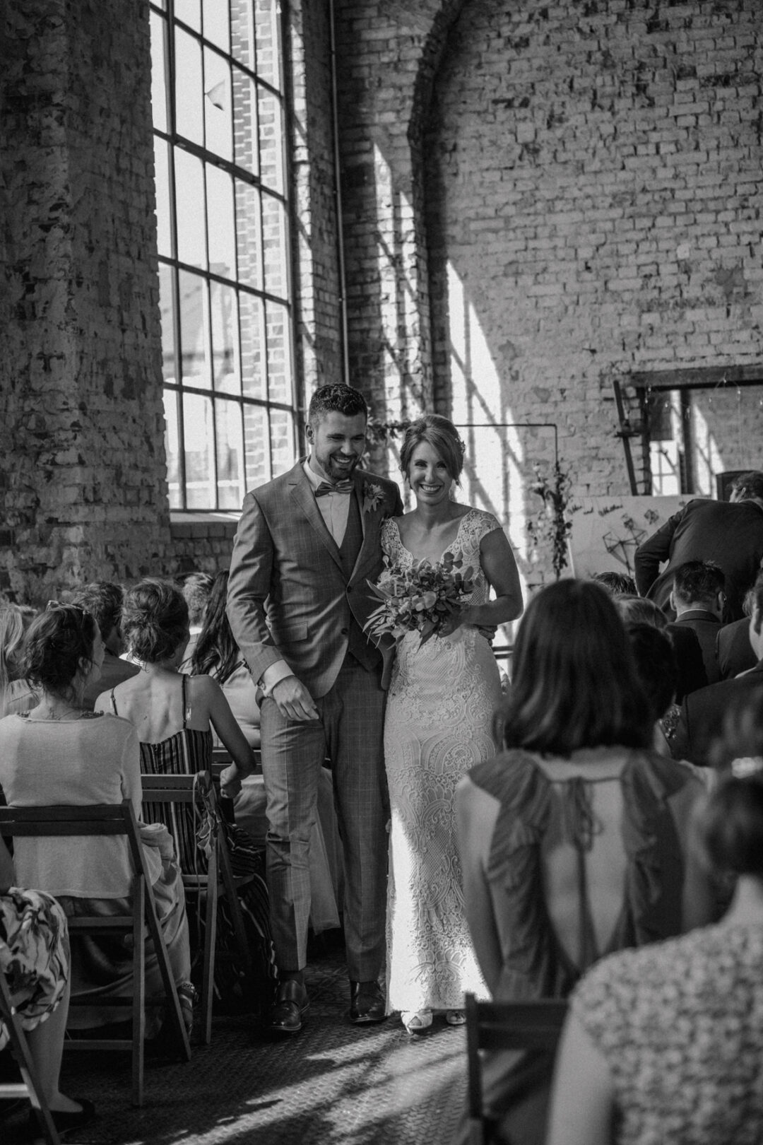 Braut und Bräutigam lächelnd beim Auszug nach der Trauung in der Maschienenhalle Waltrop