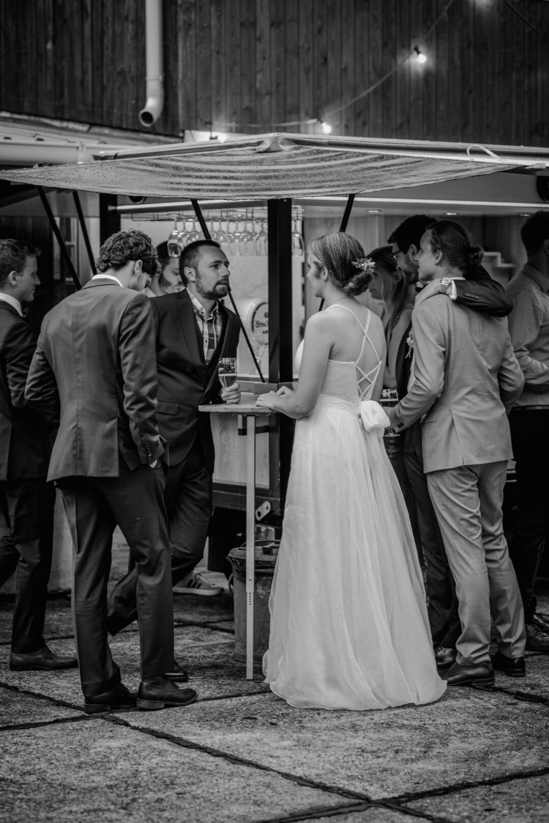 Braut spricht mit Gästen an rustikaler Theke