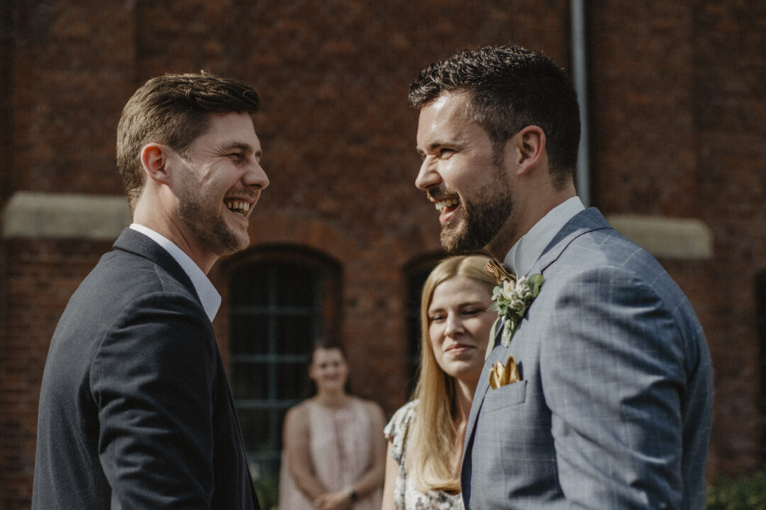Bräutigam lacht mit einem Freund nach der Hochzeit im Gasthaus Stromberg