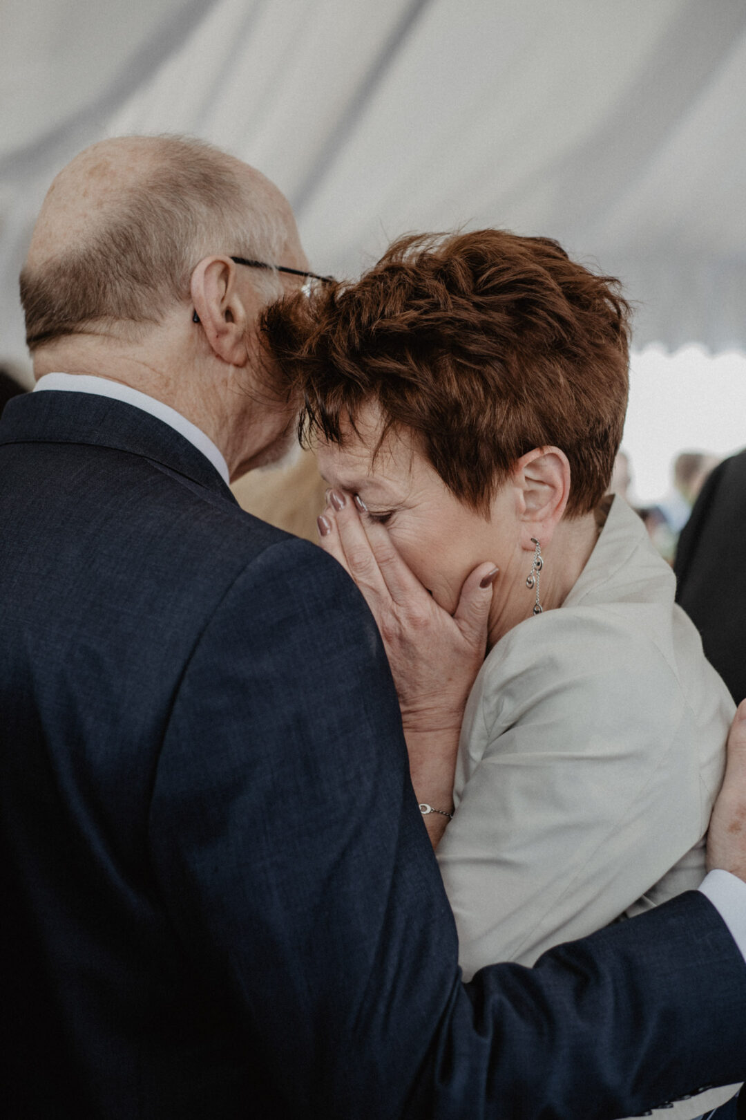 Eltern umarmen sich gerührt nach der Zeremonie