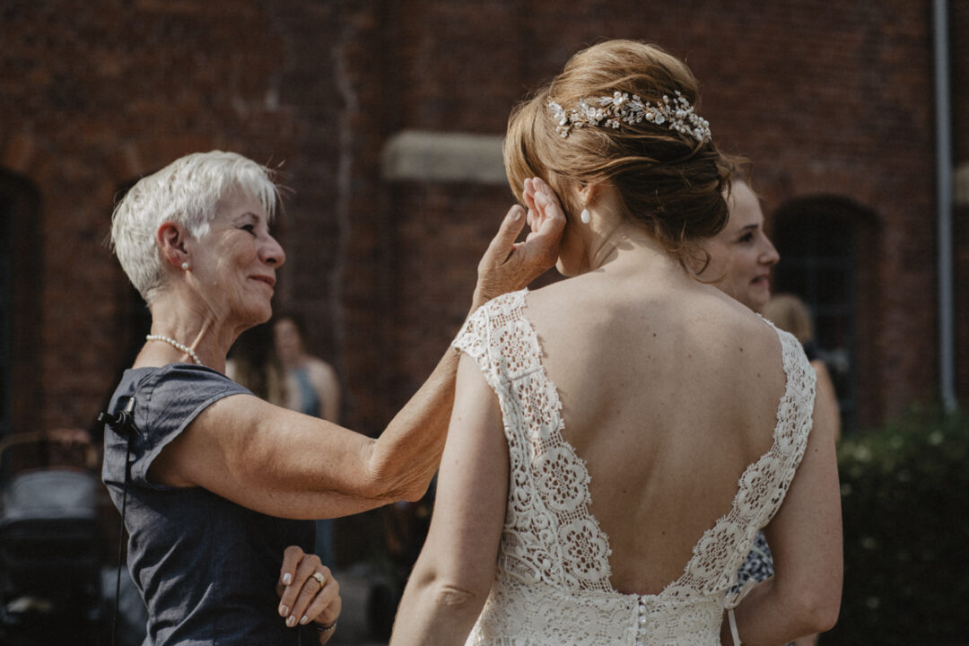 Eine ältere Frau berührt liebevoll die Braut während der Gratulation