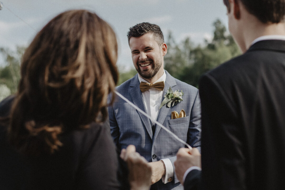 Bräutigam lacht herzlich beim Sektempfang nach der Hochzeit in Waltrop