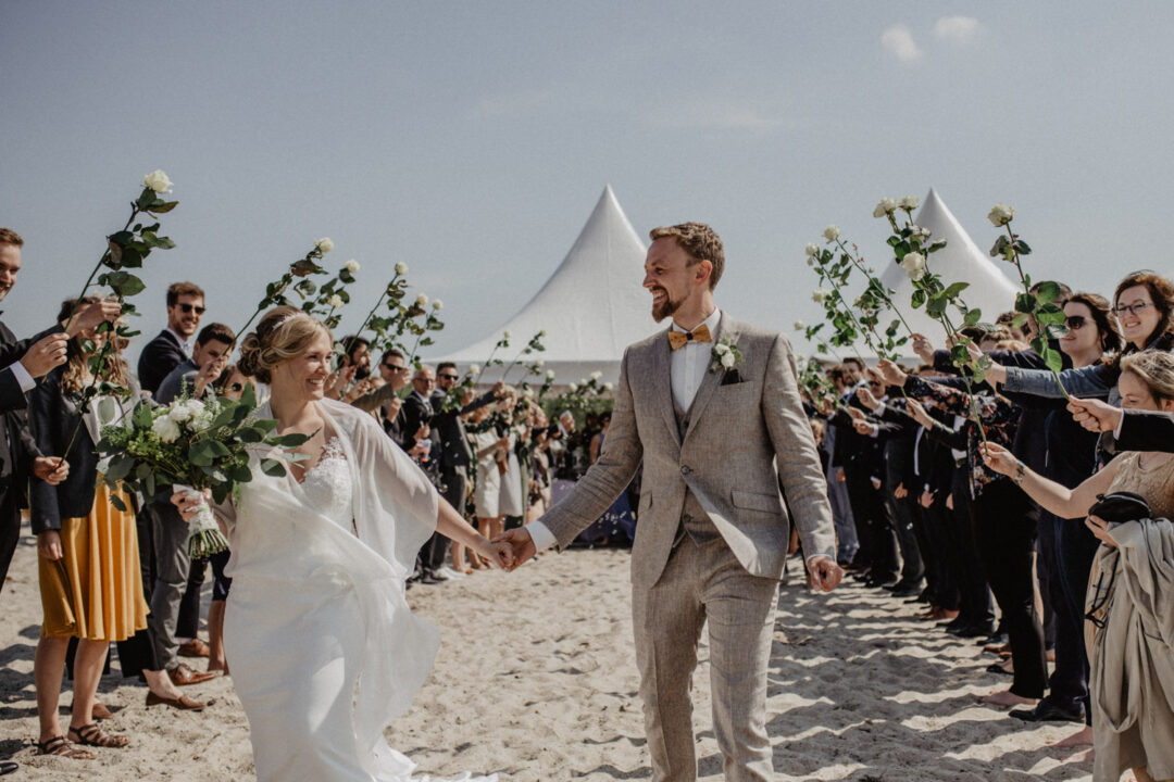 Brautpaar läuft durch Spalier mit Blüten