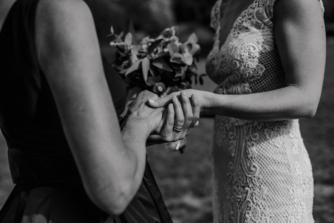 Nahaufnahme von zwei Frauen, die sich bei der Hochzeit an den Händen halten