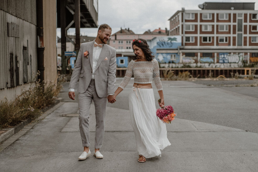 Brautpaar geht Hand in Hand durch Industriegebiet