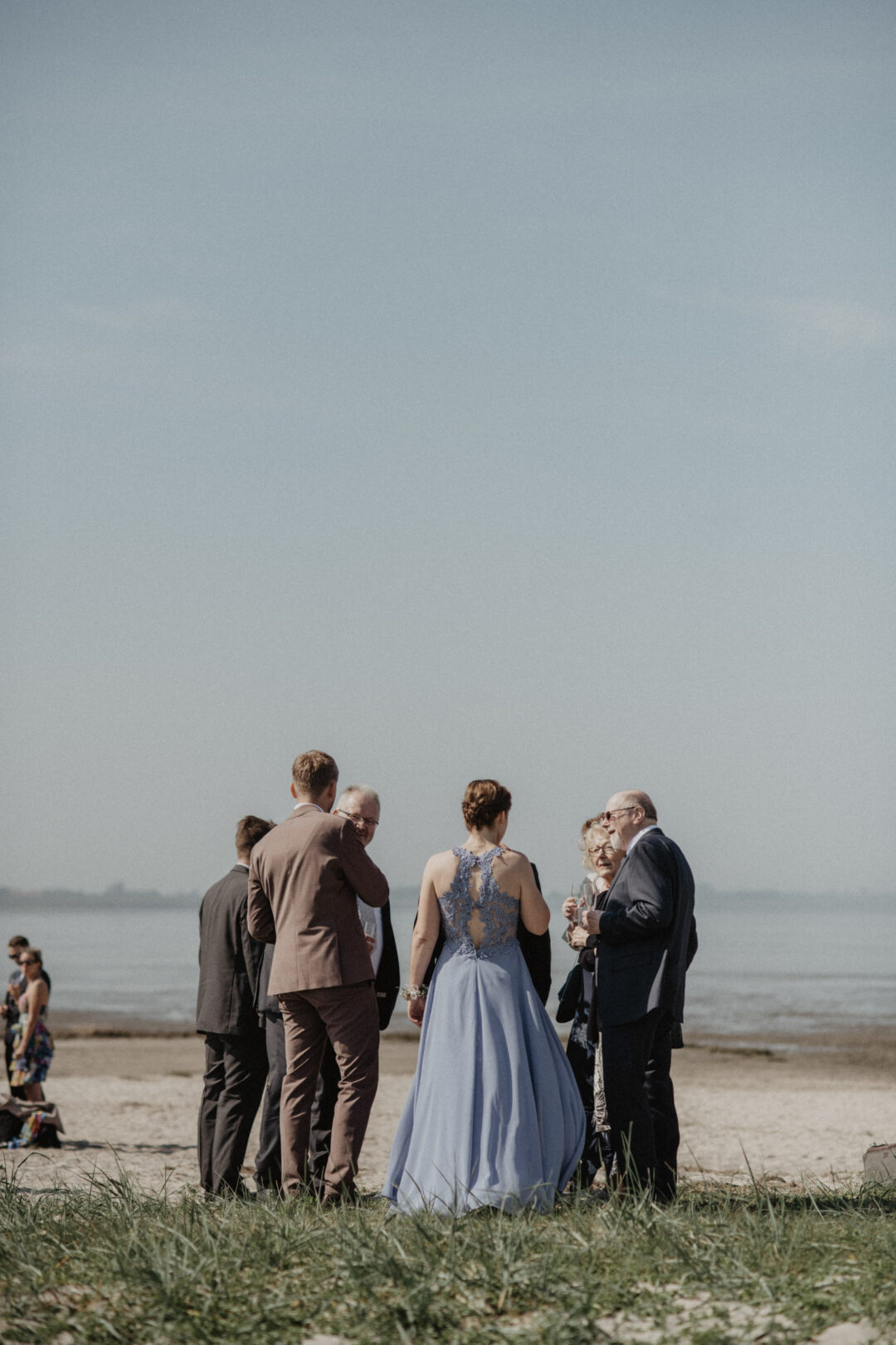 Hochzeitsgesellschaft steht am Strand