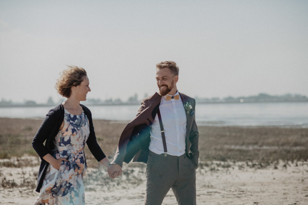 Hochzeitsgäste spazieren nach der Zeremonie am Strand entlang