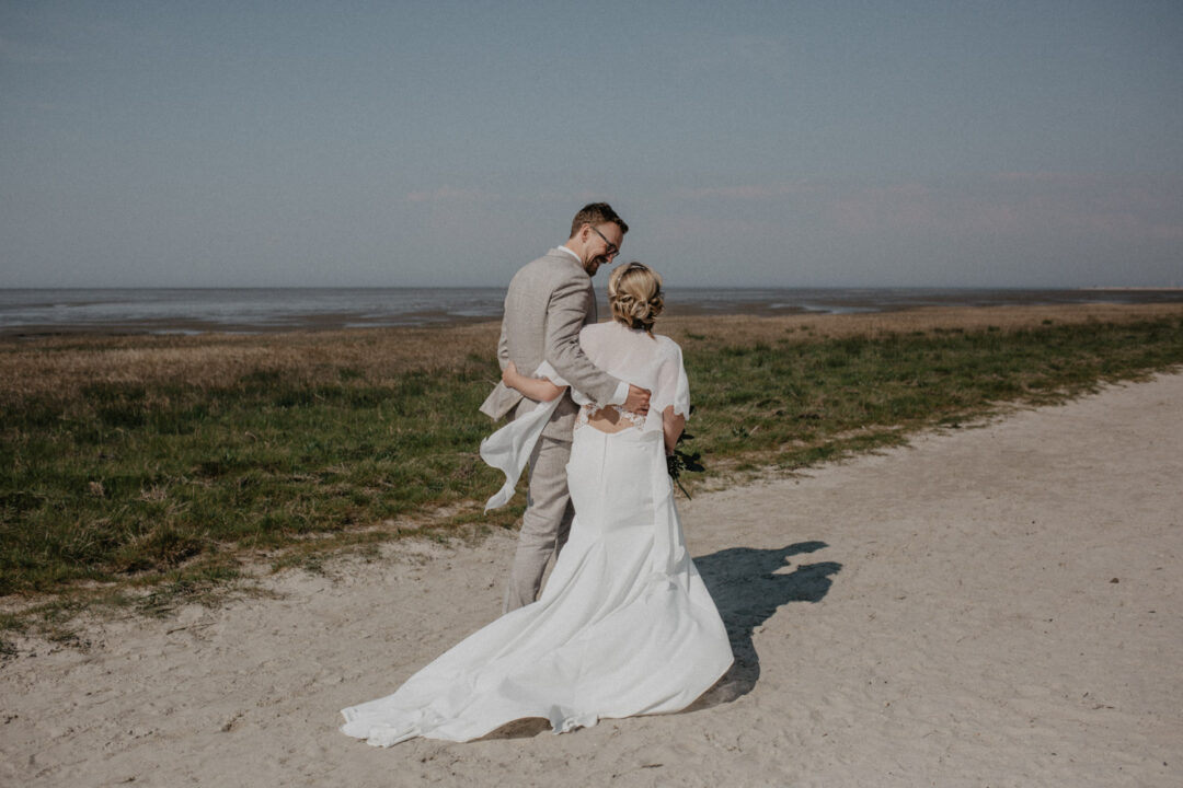 Bräutigam hebt Braut hoch, sie lachen gemeinsam