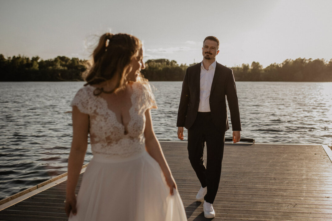 Braut und Bräutigam auf dem Holzsteg am Wasser