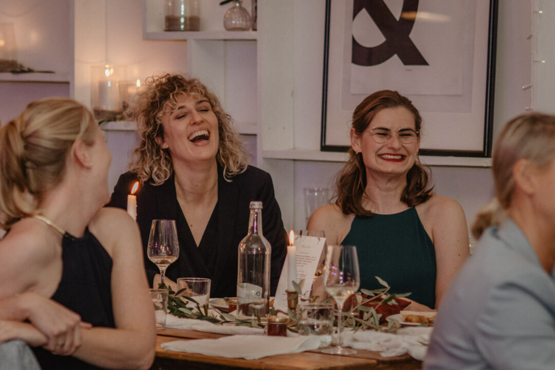 Hochzeitsgäste lachen gemeinsam bei Kerzenschein