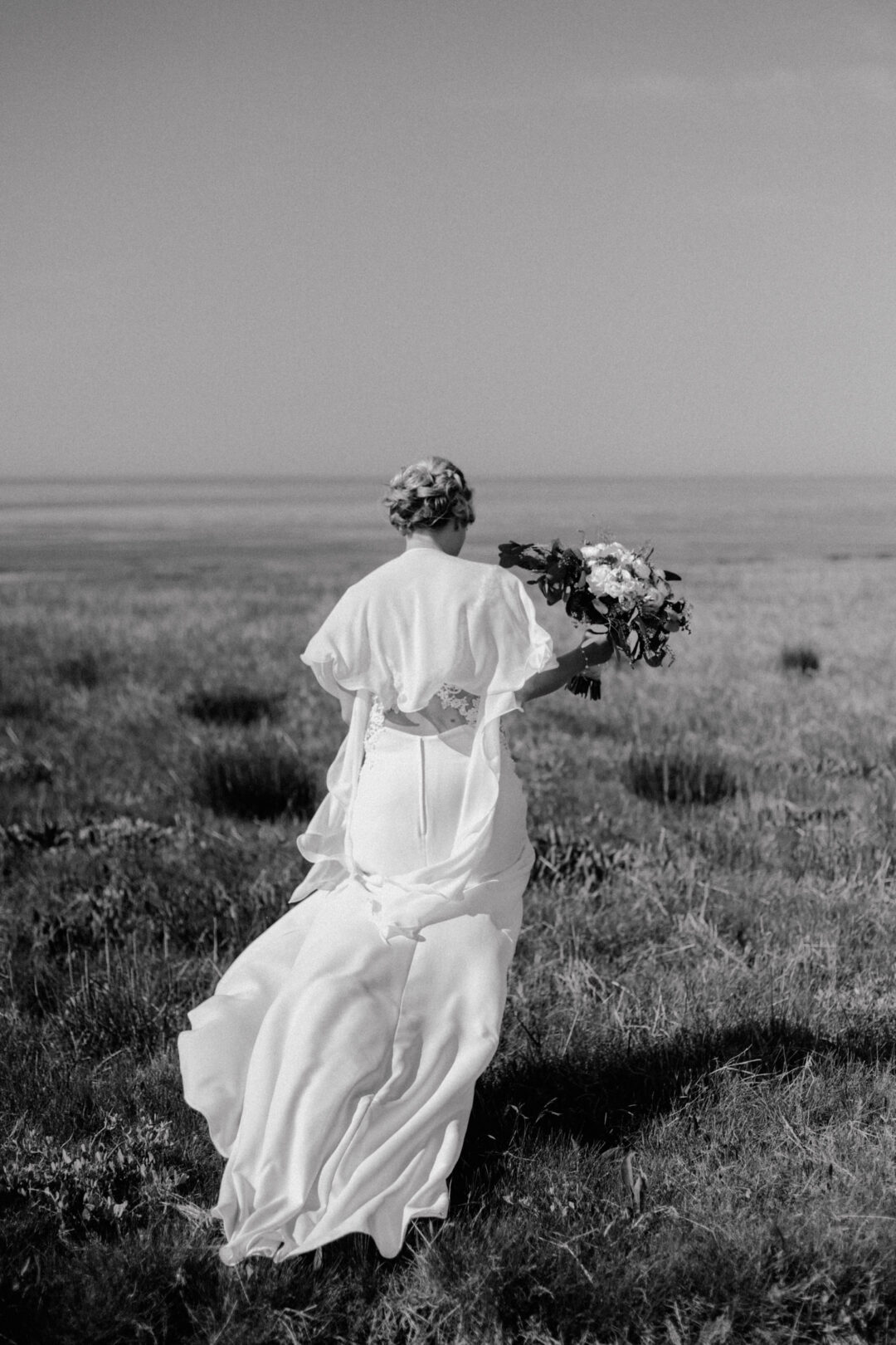 Die Braut läuft mit ihrem Brautstrauß durch die Landschaft
