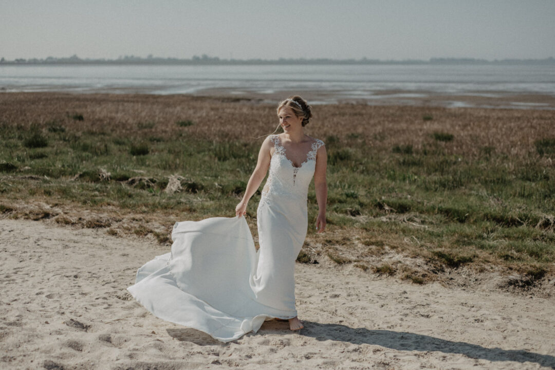 Braut geht barfuß durch den Sand