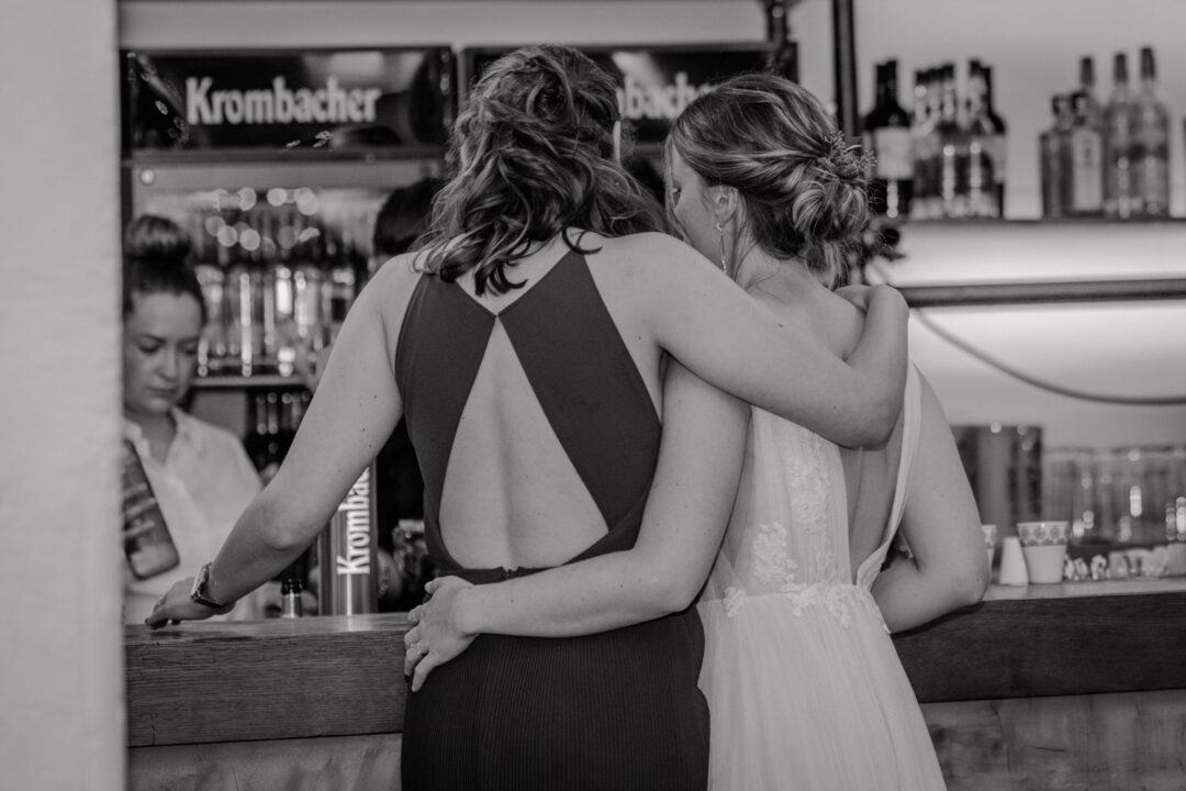 Braut umarmt Freundin an der Bar während der Hochzeit