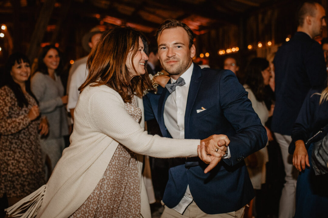 Gäste tanzen ausgelassen auf der Hochzeitsfeier in rustikaler Scheune