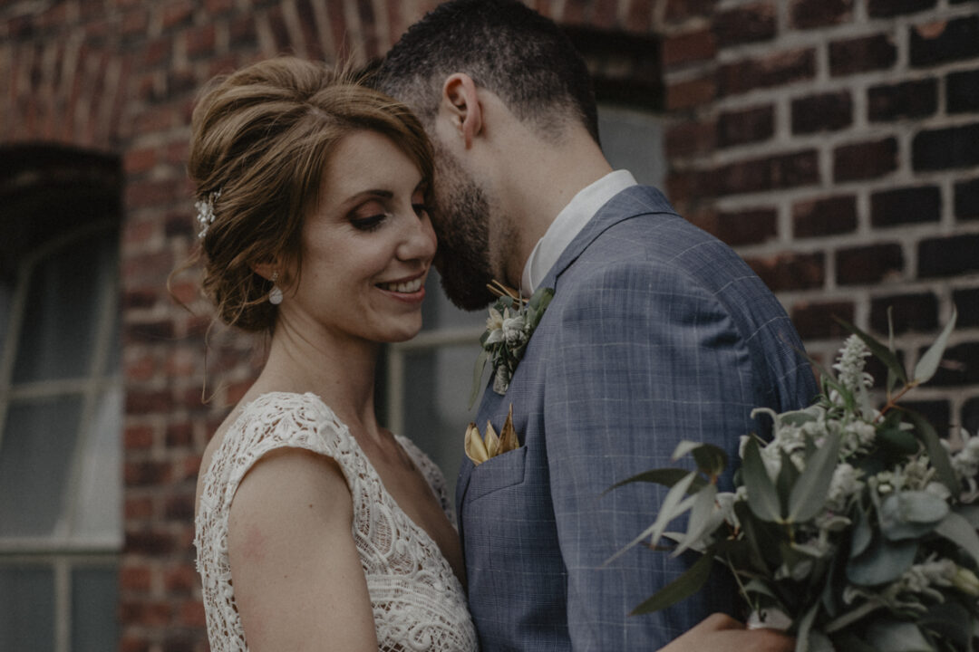 Hochzeitspaar posiert vor industrieller Backsteinfassade