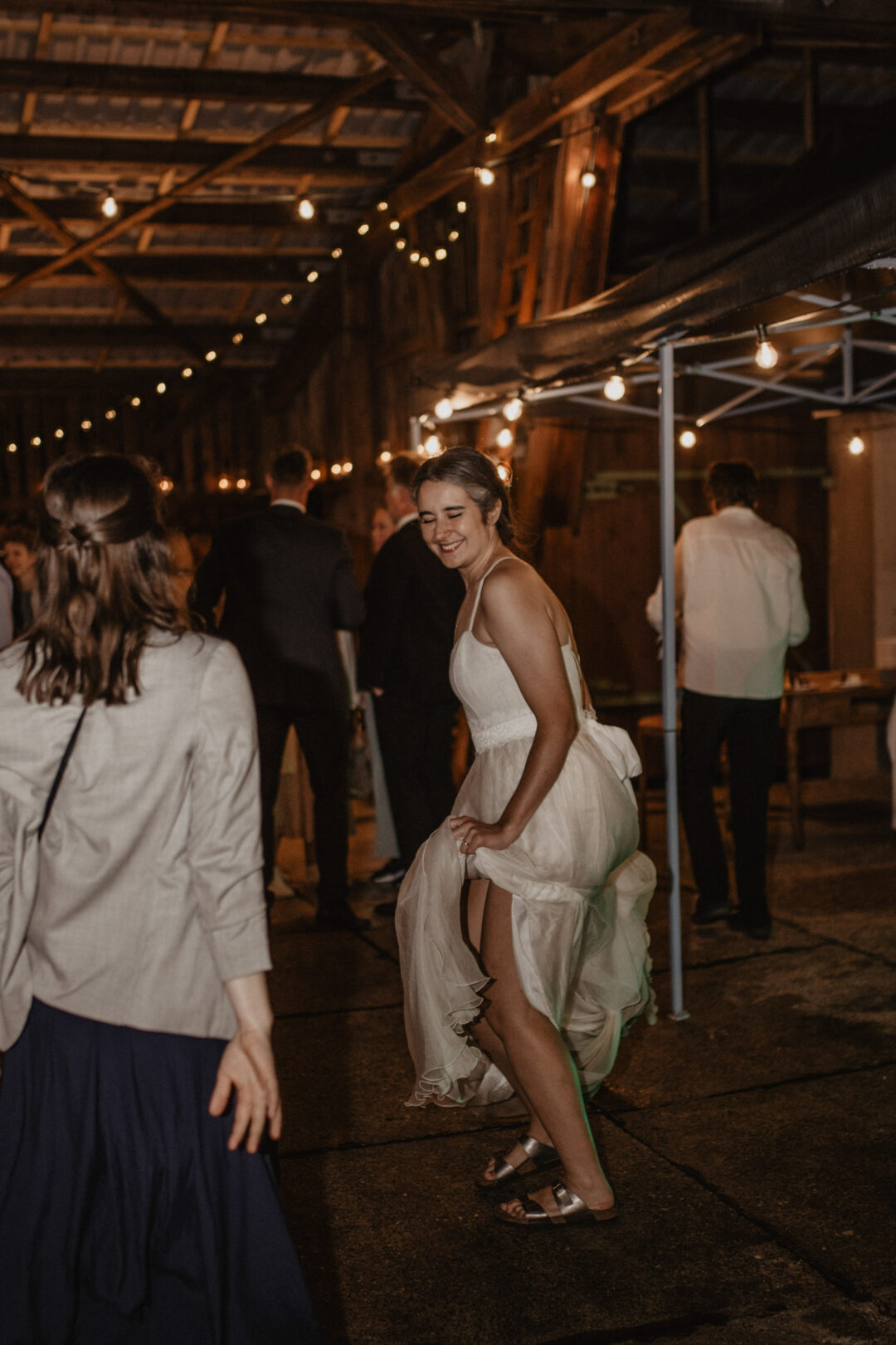 Braut tanzt barfuß und lachend auf der Hochzeitsparty