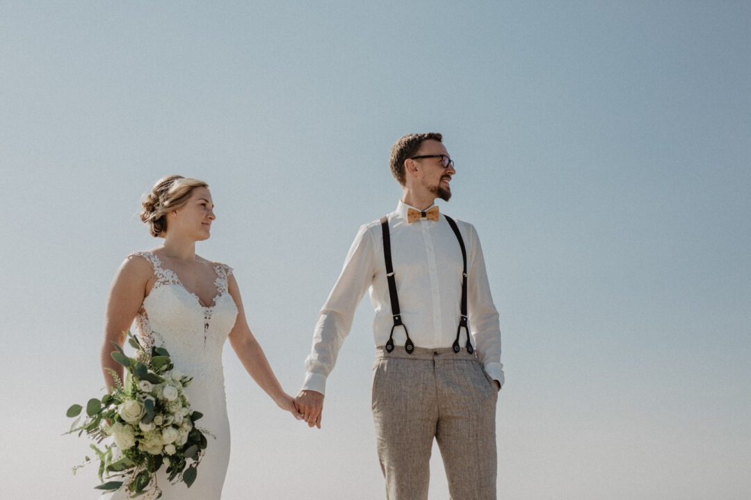 Brautpaar geht Hand in Hand am Meer entlang