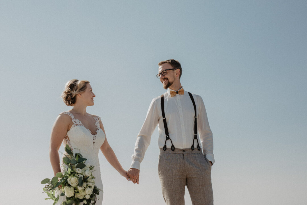 Braut und Bräutigam stehen nebeneinander unter blauem Himmel