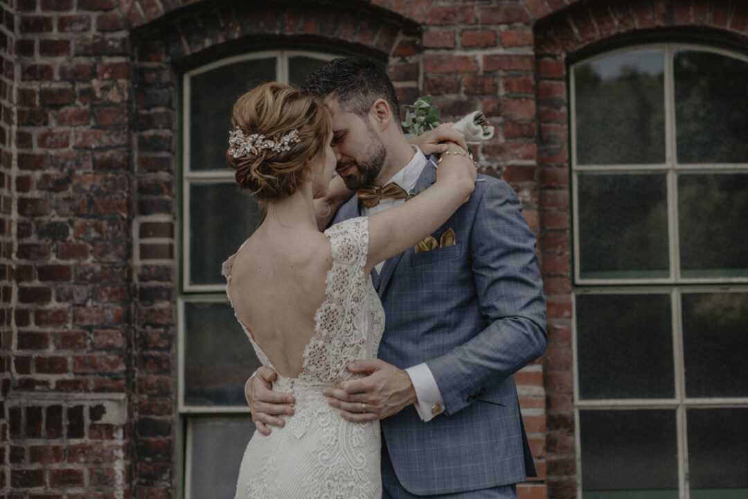 Brautpaar umarmt sich verliebt vor alter Industrie-Fassade