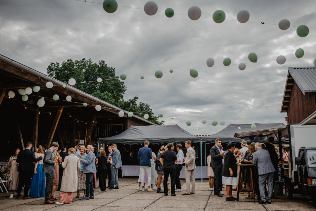 Gäste unter grünen und weißen Ballons bei Tageslicht