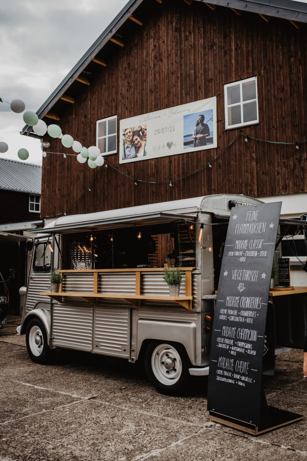 Foodtruck bei Hochzeit vor Holzscheune mit Menütafel