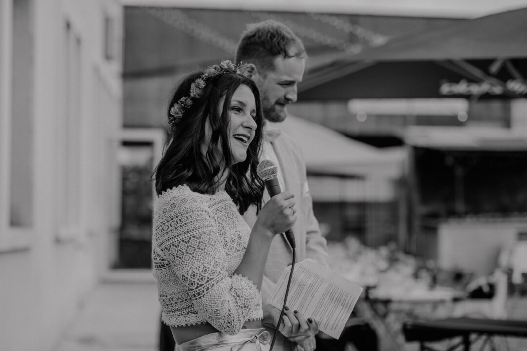 Braut spricht lachend zur Hochzeitsgesellschaft