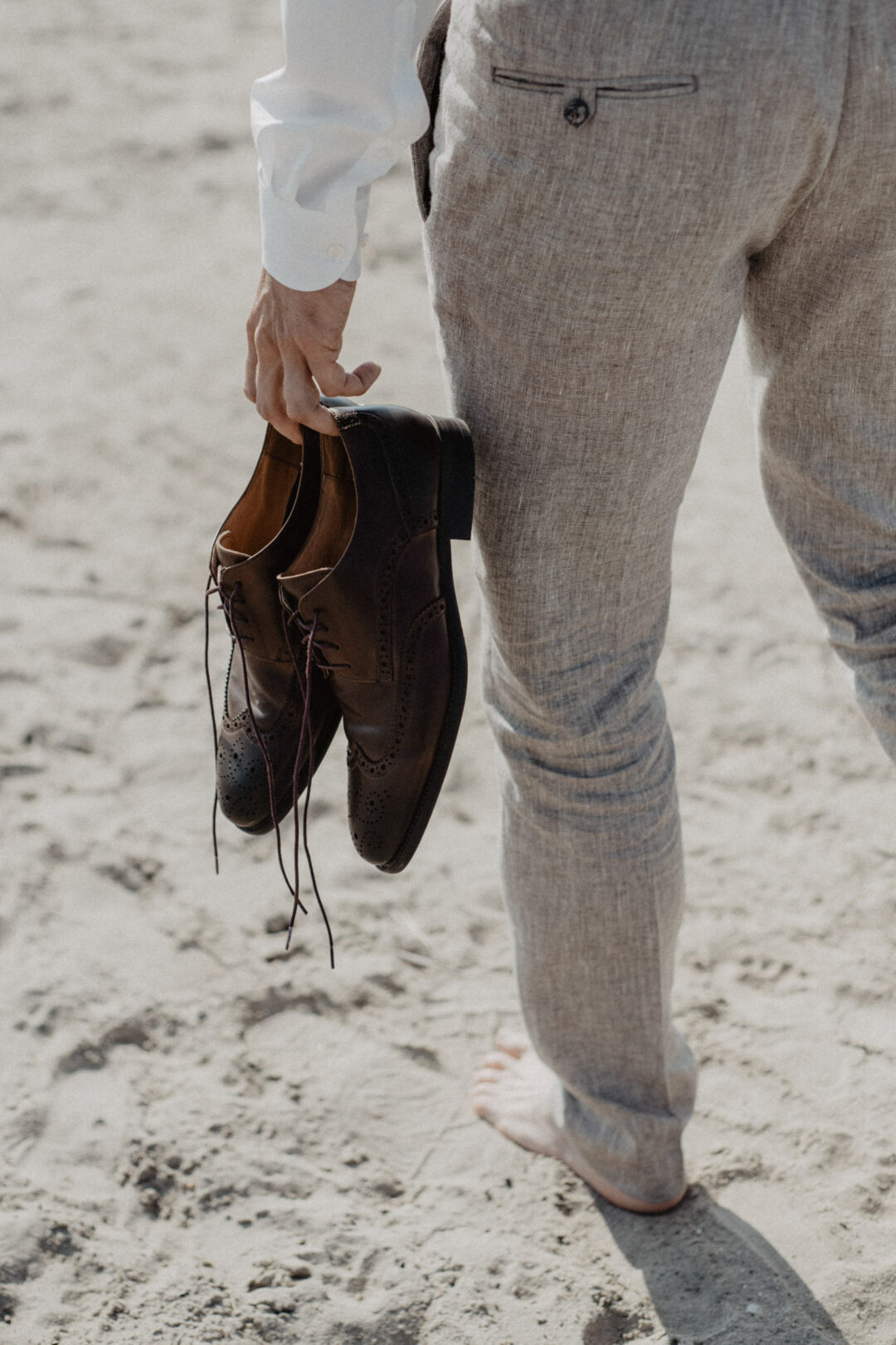 Bräutigam trägt seine Schuhe barfuß in der Hand