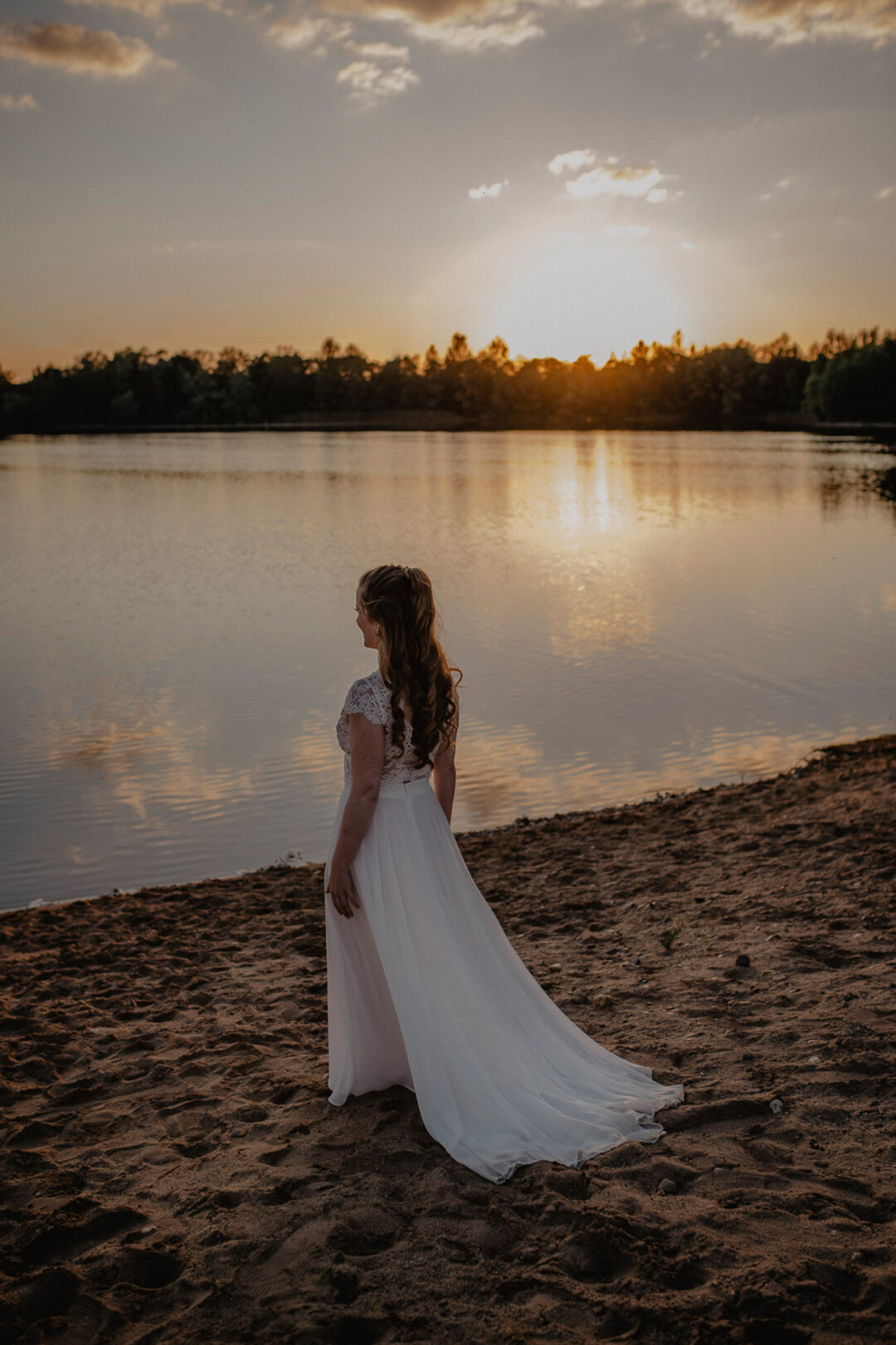 Braut steht allein am Wasser