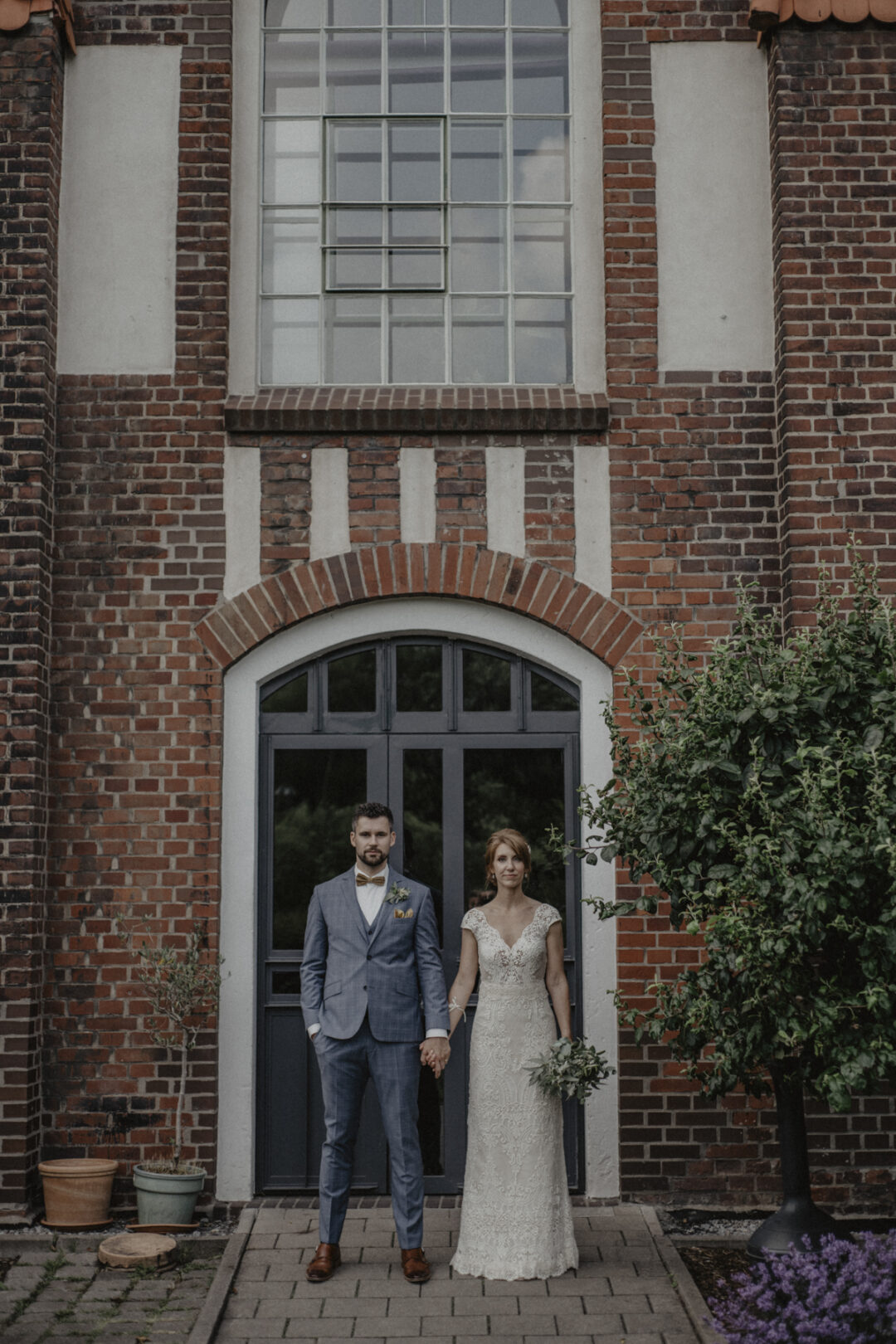 Hochzeitspaar steht vor beeindruckender Industrie-Architektur