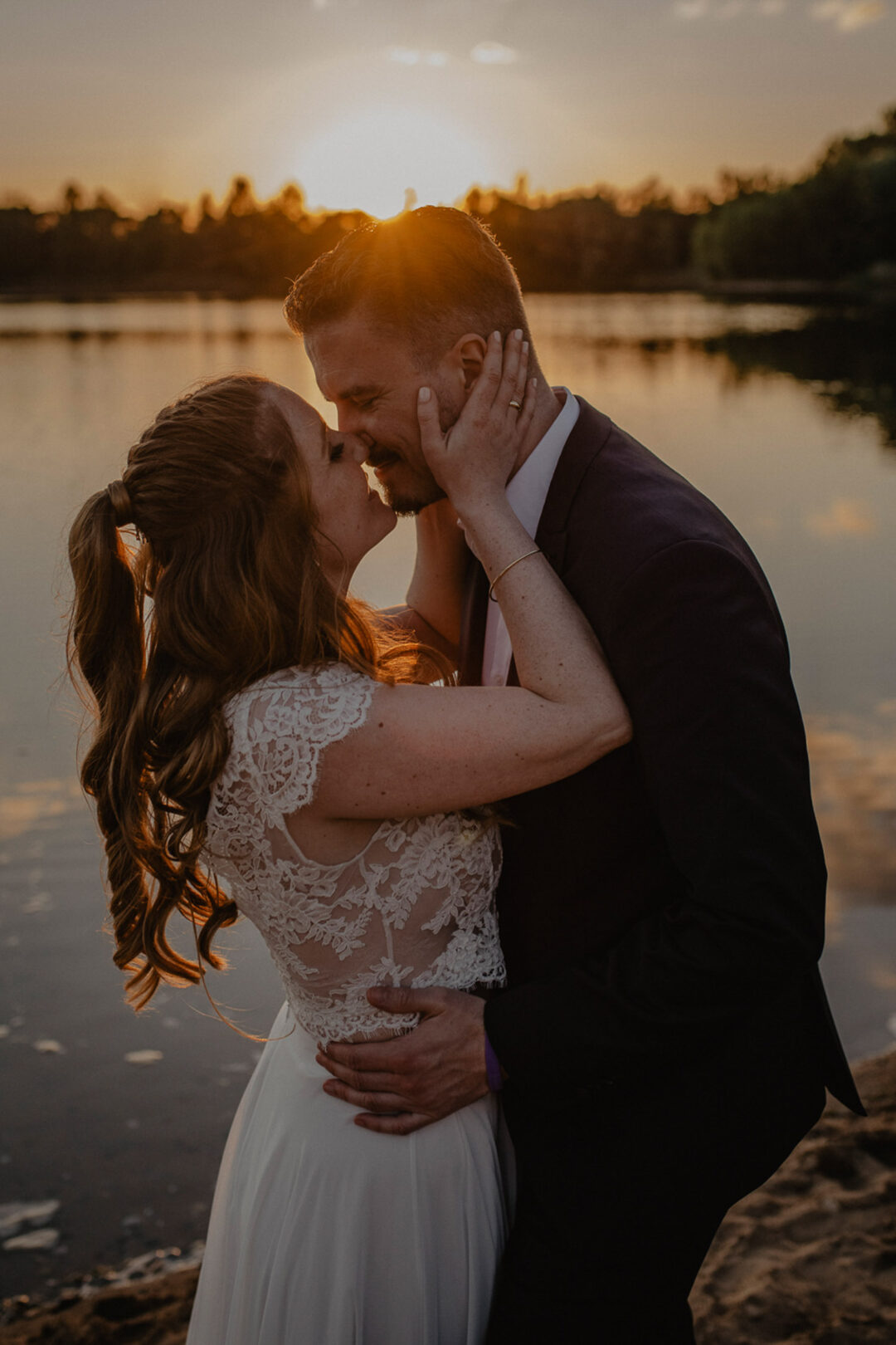 Braut küsst Bräutigam bei Sonnenuntergang