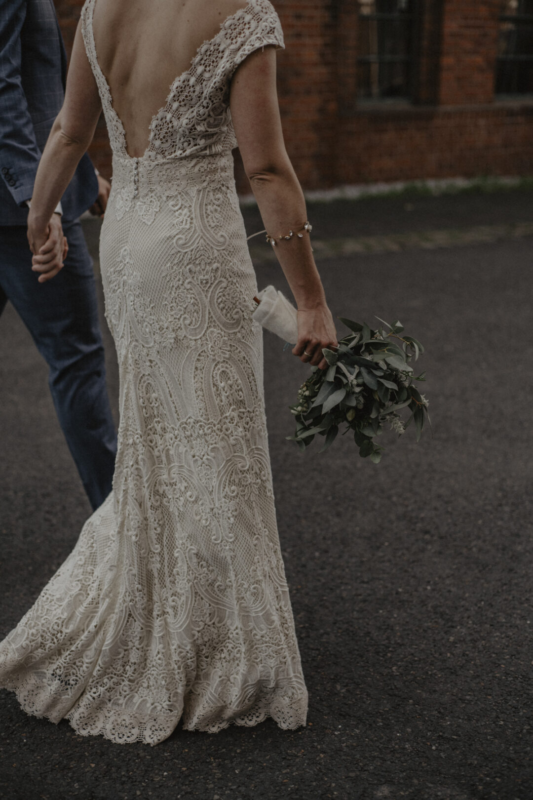 Detailaufnahme des Brautkleids vor roter Backsteinwand