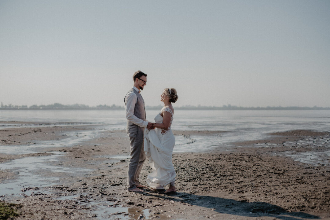 Brautpaar spaziert entspannt entlang der Küste