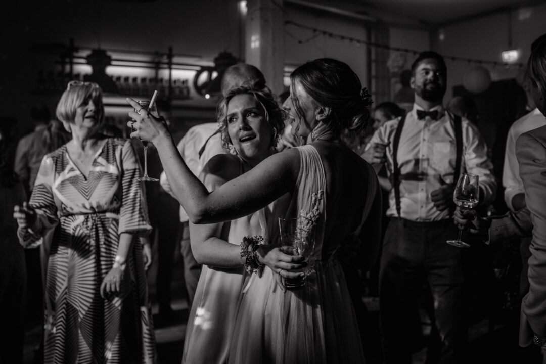 Braut und Freundin lachen laut auf der Tanzfläche