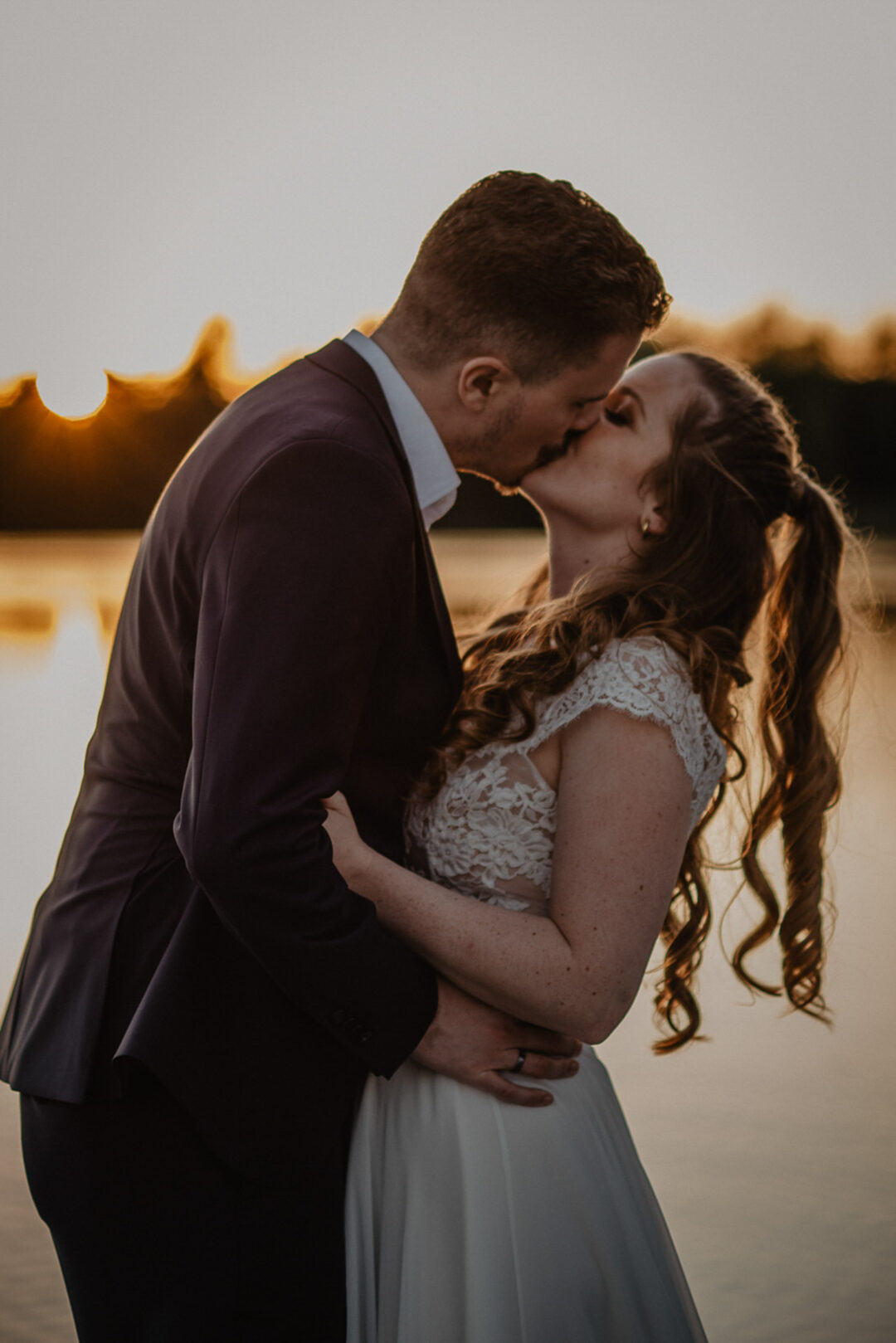 Hochzeitspaar küsst sich am See