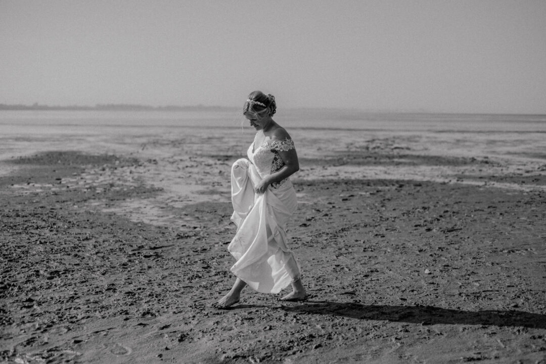 Die Braut läuft in Schwarz-Weiß durchs Watt