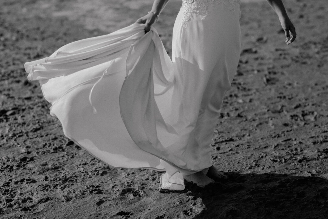 Das Kleid der Braut weht im Wind beim Gehen