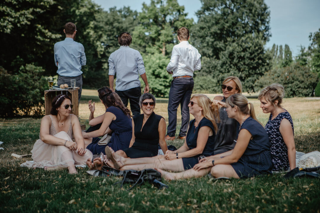 Hochzeitsgäste sitzen beim Picknick auf der Wiese