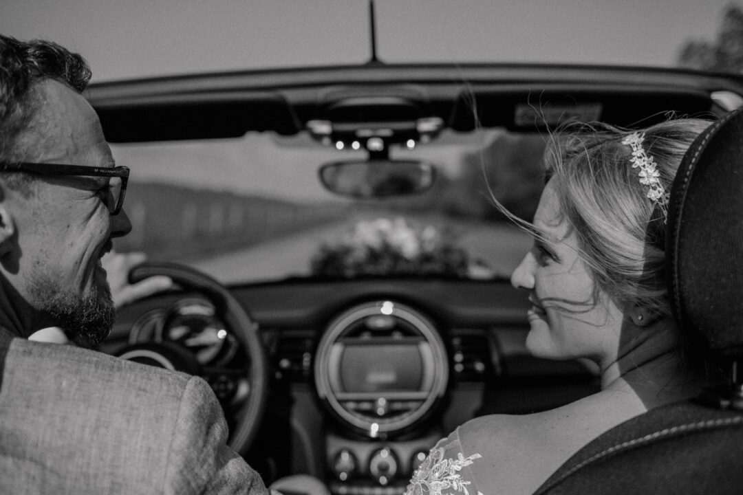 Brautpaar fährt gemeinsam im Cabrio zur Feier