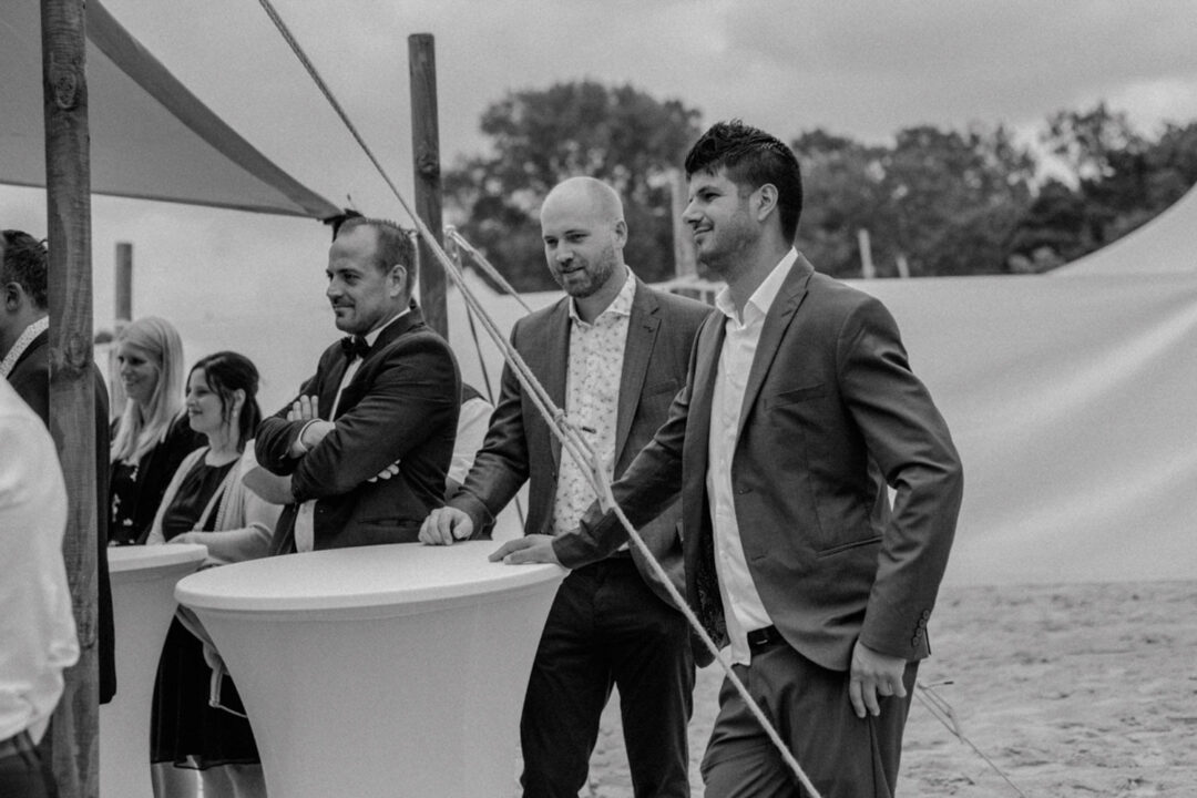 Hochzeitsgäste im Anzug warten am Trauzelt am Fühlinger See