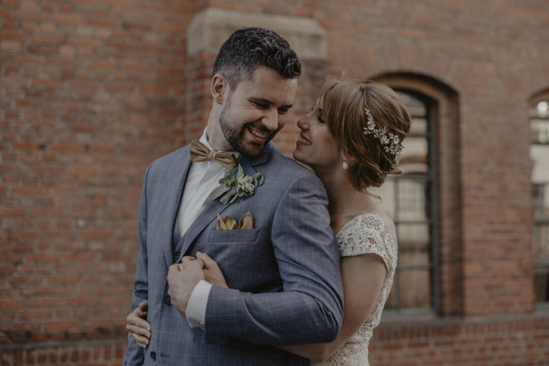 Glückliches Brautpaar vor Backsteinfassade in Waltrop