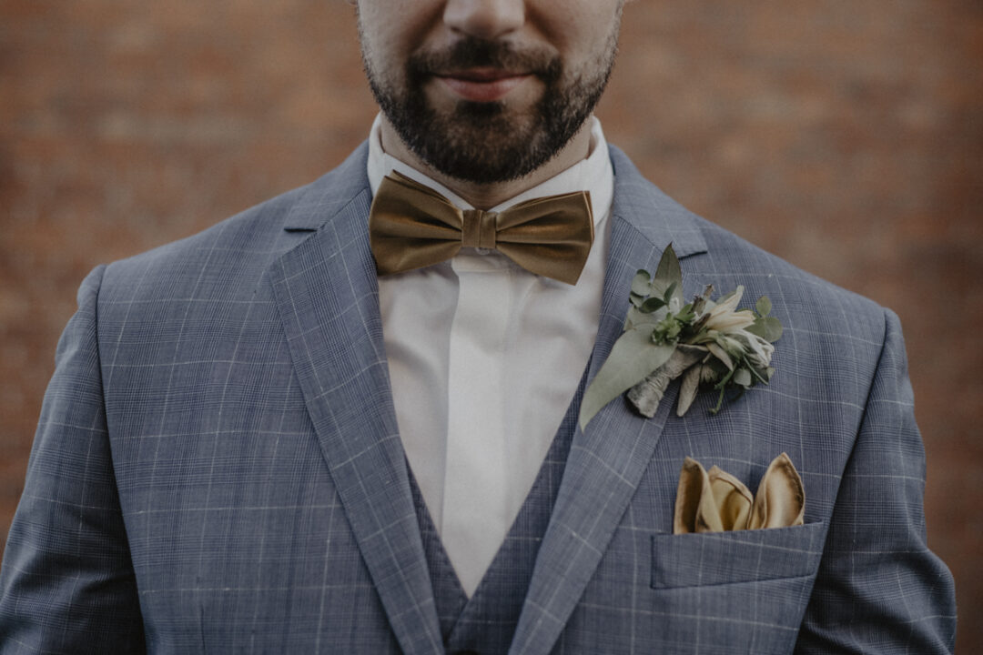 Detailaufnahme der goldenen Fliege des Bräutigams auf der Hochzeit in NRW
