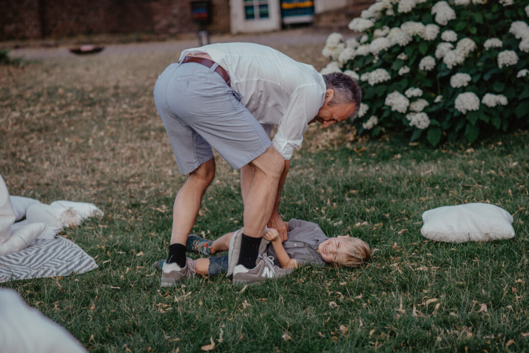 Vater spielt mit Kind auf Wiese bei Hochzeit