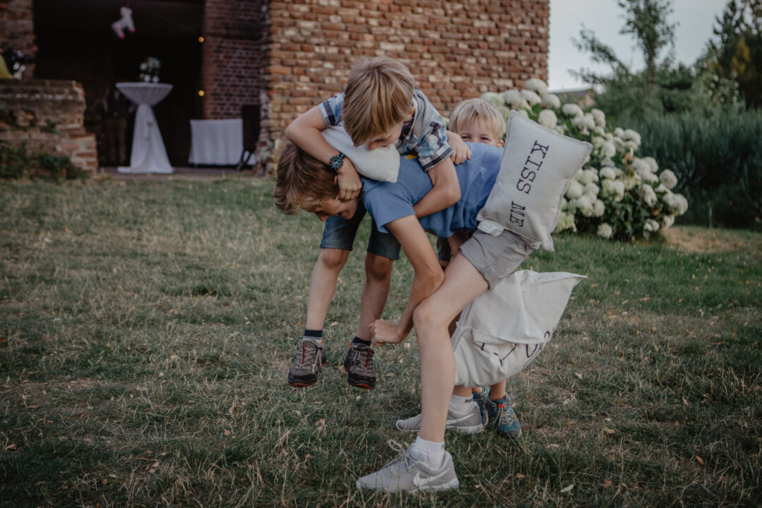 Kinder spielen ausgelassen mit Kissen im Garten