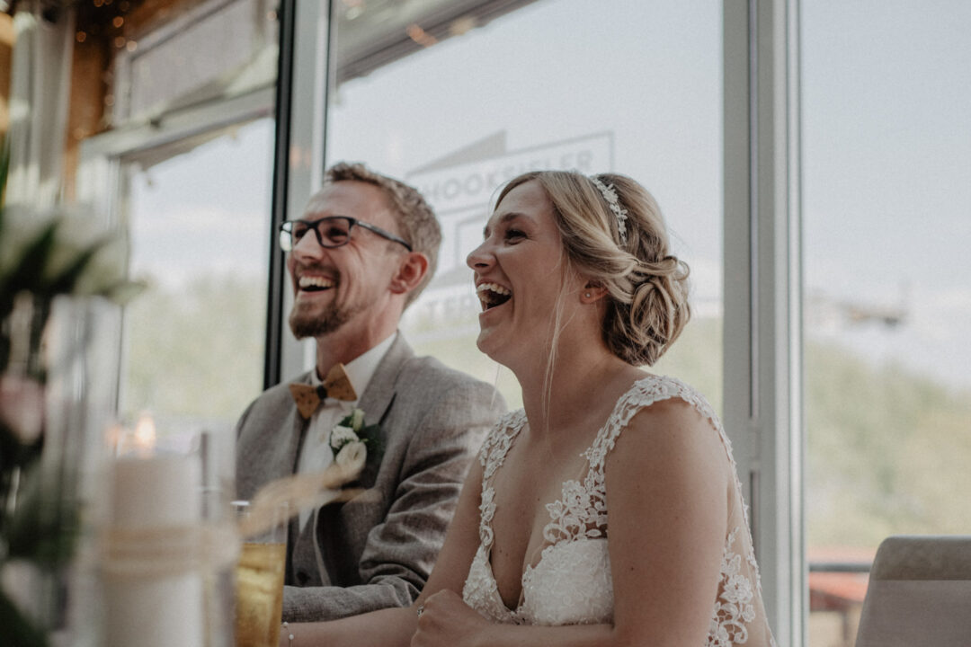 Brautpaar lacht bei der Rede während der Feier