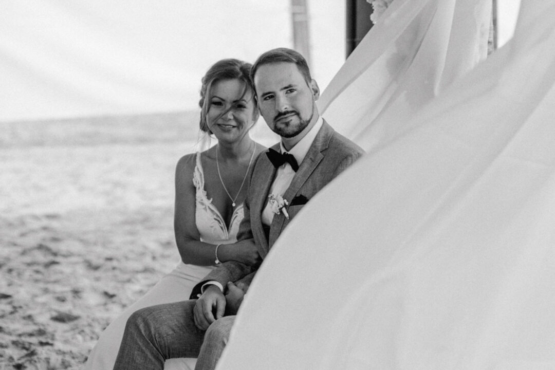 Brautpaar am Strand blickt ruhig während Trauung nach vorne