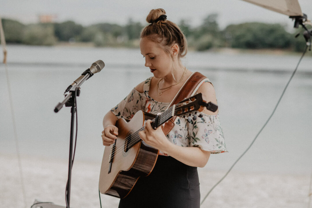 Musikerin singt mit Gitarre bei der freien Trauung am Wasser