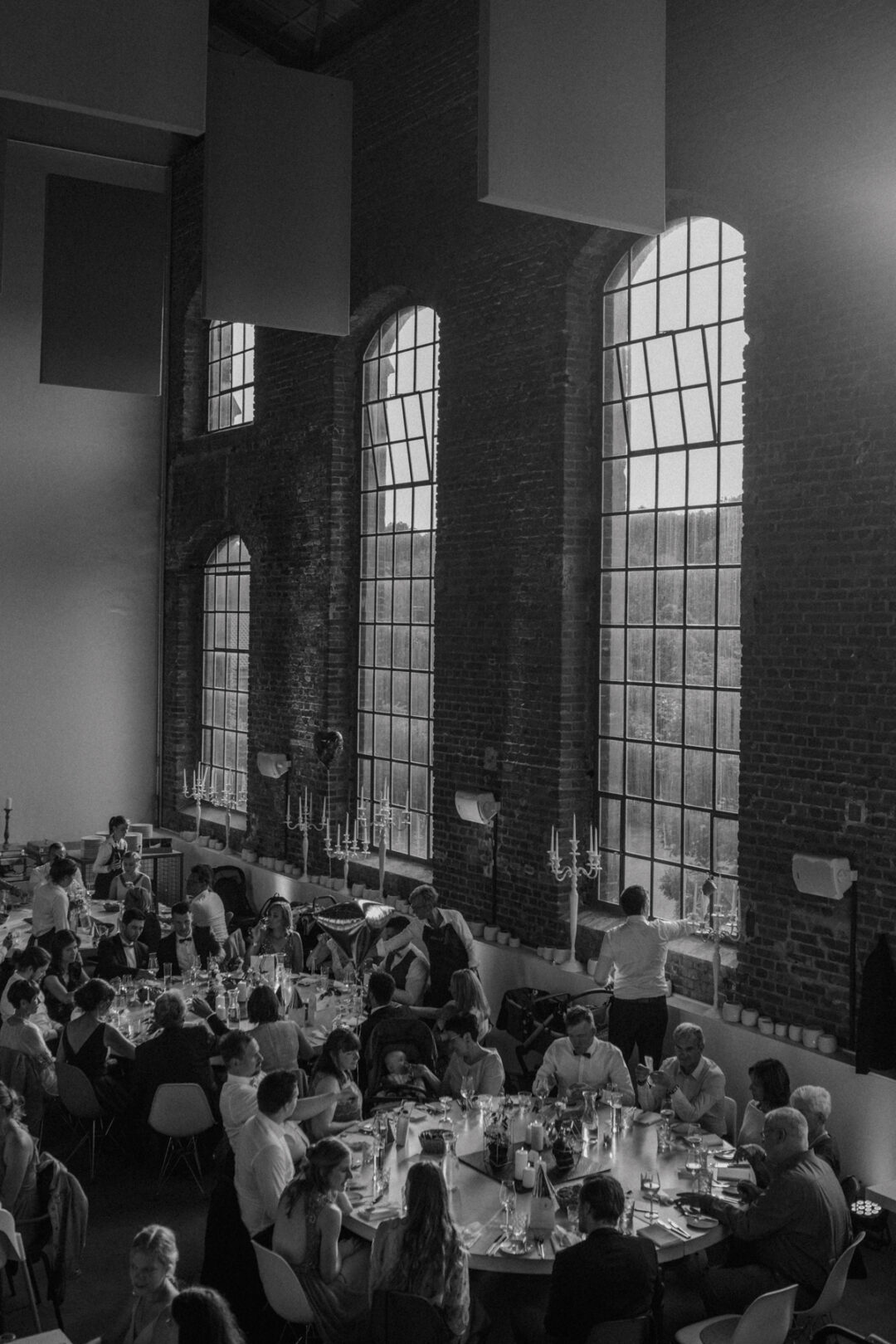 Hochzeitsgäste an langer Tafel in Industriekulisse