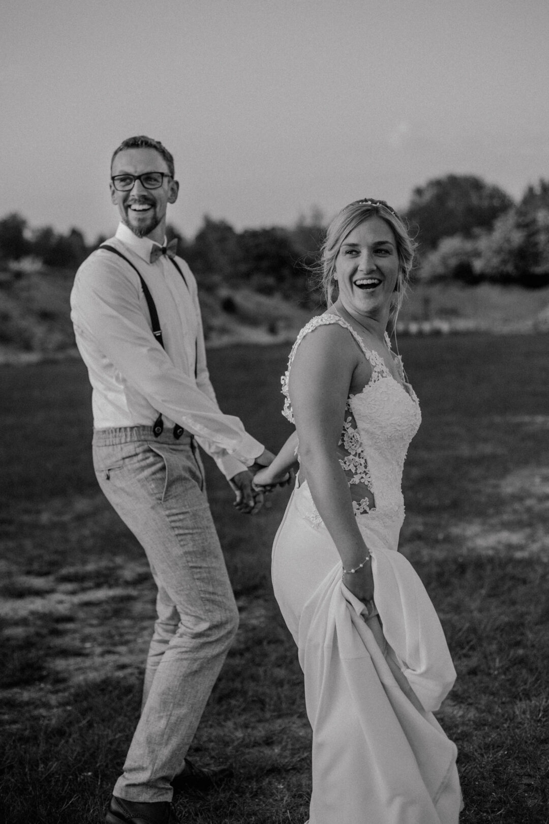 Braut und Bräutigam laufen lachend nebeneinander