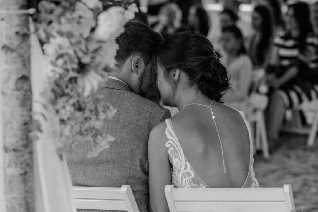Blick von hinten auf das Brautpaar unter dem floralen Traubogen